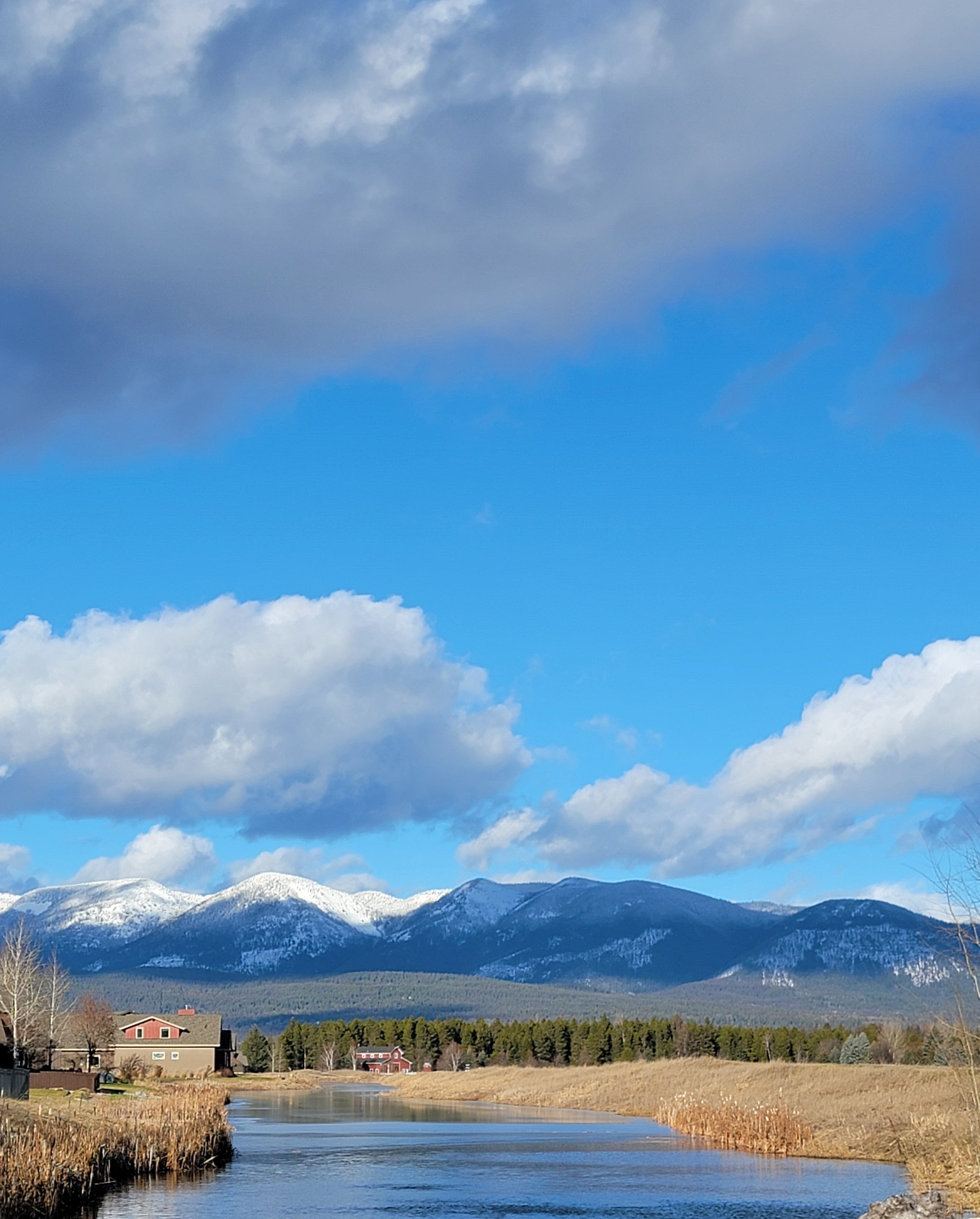 Reflective surface with mountains, sky, and clouds